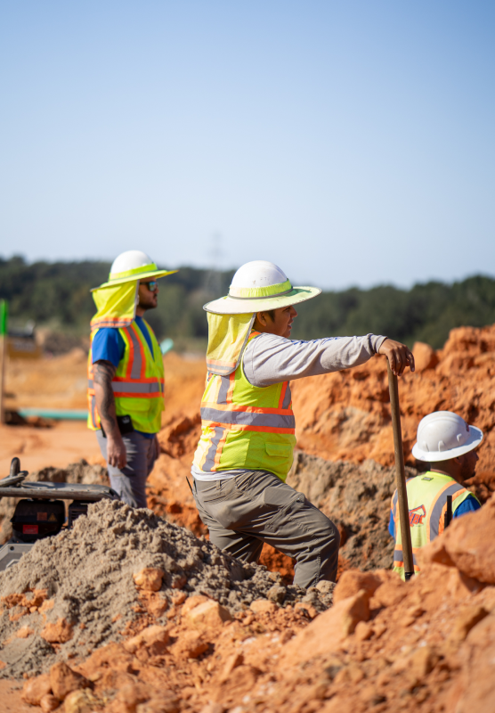 HBC, three employees standing, different levels, red dirt, wide brimmed hard hats, white hard hat, blue t shirt, grey long sleeve shirt, leaning on shovel stick, are-you-ready-to-join-hbc.png, Culture